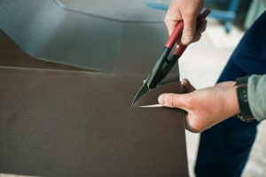 close up of a Worker hands use scissors to cut the metal sheet.